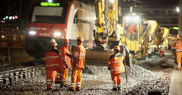 workers and machines working on a railway at night