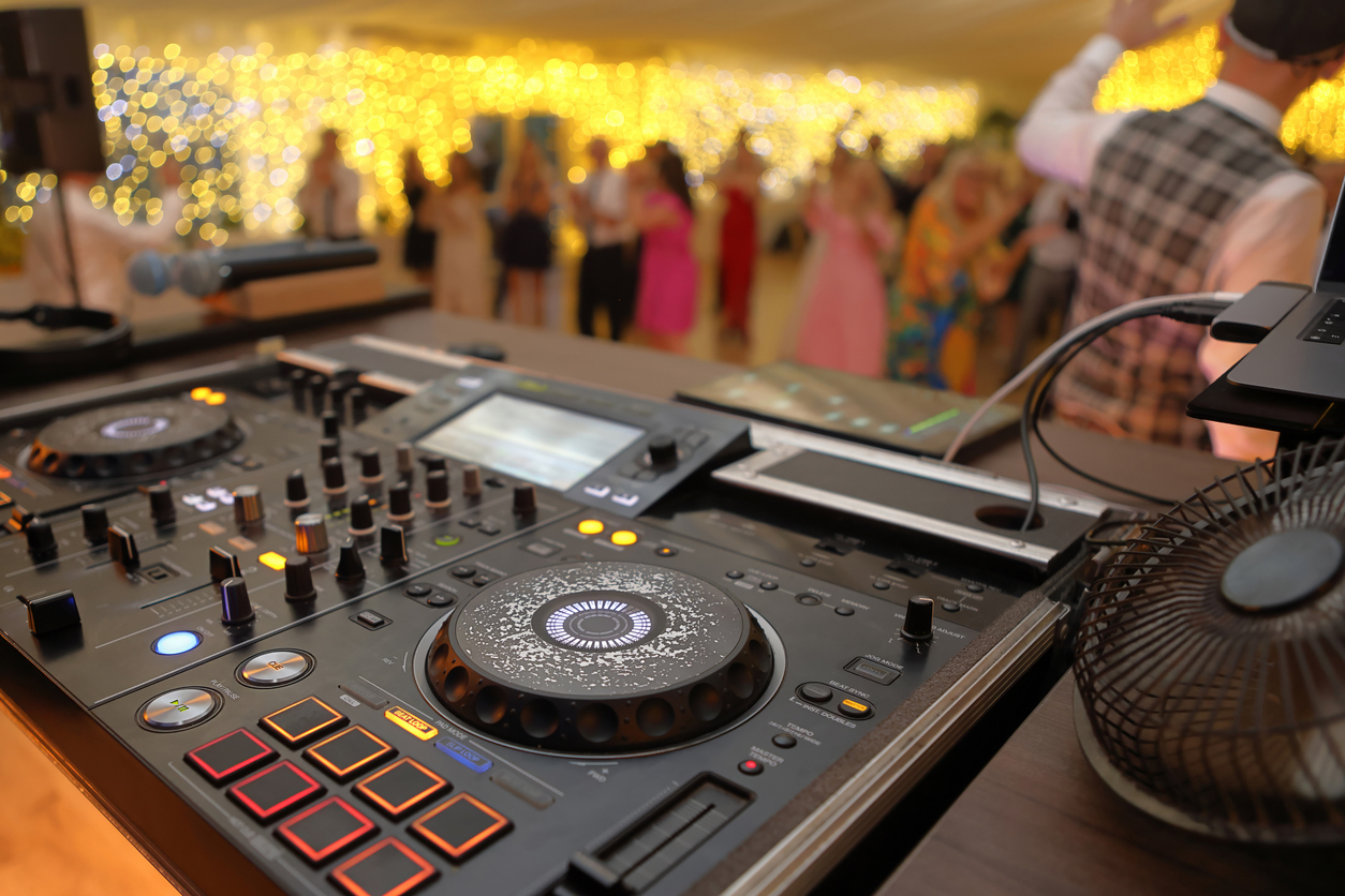 A DJ deck with a loud wedding party in the background